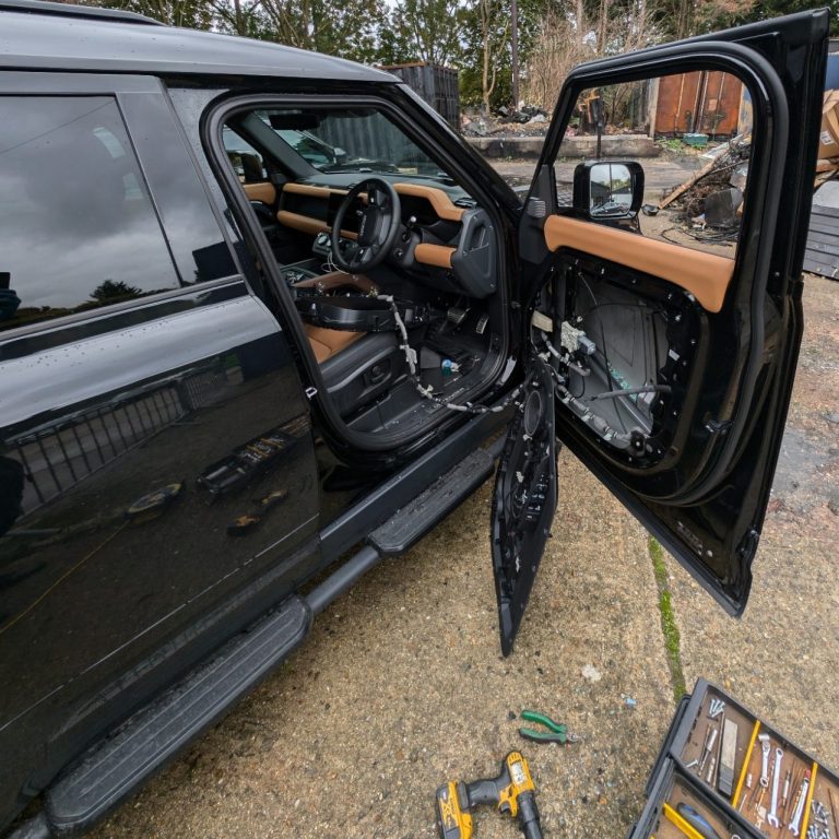 A Land Rover Defender parked up in London with its side window smashed, showcasing front window replacement service by Epic Windscreens.